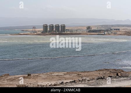 Acque di lago salato LAC Assal con una fabbrica di estrazione del sale sullo sfondo, il punto più basso dell'Africa, regione di Tadjourah, Gibuti Foto Stock