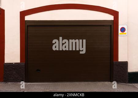 Porta del garage chiusa di colore marrone con finiture rosse e nessun segnale di parcheggio Foto Stock