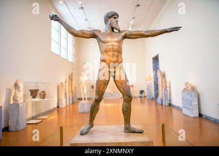 ATENE, Grecia — la statua di Zeus o Poseidone, una scultura in bronzo impressionante del V secolo a.C., è una delle mostre più famose presso il Museo Archeologico Nazionale di Atene. Si ritiene che questa iconica scultura, scoperta nel mare al largo di Capo Artemision, rappresenti Zeus, che regge un fulmine, o Poseidone, che brandisce un tridente. La statua è celebrata per la sua posa dinamica e l'intricata maestria artigianale, che esemplifica l'eccellenza artistica degli antichi scultori greci. Foto Stock