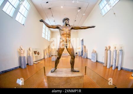 ATENE, Grecia — la statua di Zeus o Poseidone, una scultura in bronzo impressionante del V secolo a.C., è una delle mostre più famose presso il Museo Archeologico Nazionale di Atene. Si ritiene che questa iconica scultura, scoperta nel mare al largo di Capo Artemision, rappresenti Zeus, che regge un fulmine, o Poseidone, che brandisce un tridente. La statua è celebrata per la sua posa dinamica e l'intricata maestria artigianale, che esemplifica l'eccellenza artistica degli antichi scultori greci. Foto Stock