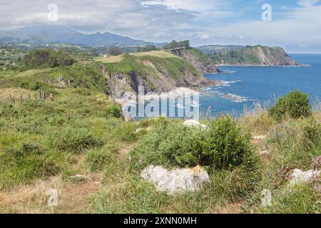 Donna in rosso che cammina accanto alle scogliere dell'Inferno, Ribadesella, Asturie orientali, Spagna Foto Stock
