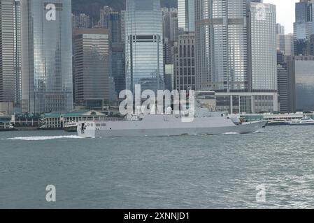 Nave da guerra della Marina che naviga lungo Victoria Harbour con i grattacieli centrali alle spalle. Hong Kong - 30 maggio 2024 Foto Stock