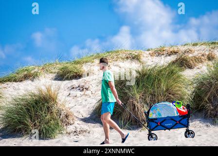 Rostock, Germania. 1 agosto 2024. I turisti si dirigono verso la spiaggia del Mar Baltico di Warnemünde con molte attrezzature. I turisti e i visitatori di un giorno approfittano del clima caldo e soleggiato per fare una gita alle spiagge del Meclemburgo-Vorpommern. Crediti: Jens Büttner/dpa/Alamy Live News Foto Stock