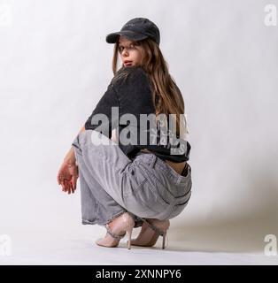 berretto con i capelli scuri, berretto grigio da donna che sfoggia un look casual da camionista in stile canotta streetstyle Foto Stock