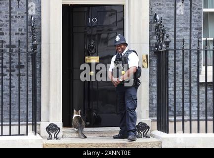 Larry, il topo residente al numero 10 in attesa di essere lasciato entrare dal britannico bobby in Downing Street, Westminster, Londra, Regno Unito Foto Stock