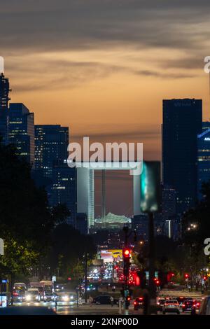 Parigi, Francia - 31 luglio 2024: La Defense grande Arche illuminata al tramonto con traffico cittadino Foto Stock