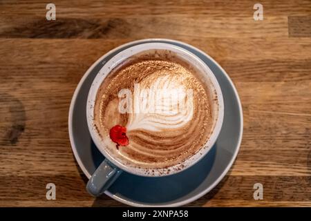 Vista dall'alto di un latte con latte art rosetta in piuma e decorazione di fiori secchi su un tavolo di legno Foto Stock