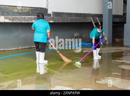 Lavoratori con spazzatrici e pavimenti in fabbrica Foto Stock