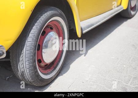 Una classica auto d'epoca gialla con un sorprendente accento rosso sul design delle ruote Foto Stock