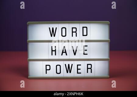 Word ha testo della carta intestata Power su scatola luminosa LED su sfondo rosa e viola Foto Stock