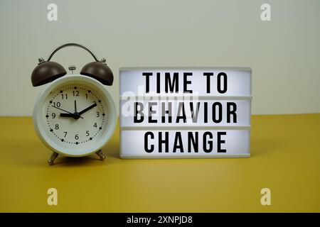 Time to Behavior Modifica il testo sulla scatola luminosa a LED con sveglia su sfondo giallo, concetto aziendale e finanziario Foto Stock