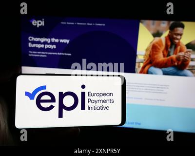 Persona che detiene uno smartphone con il logo della società europea European Payments Initiative (EPI) davanti al sito web. Mettere a fuoco il display del telefono. Foto Stock