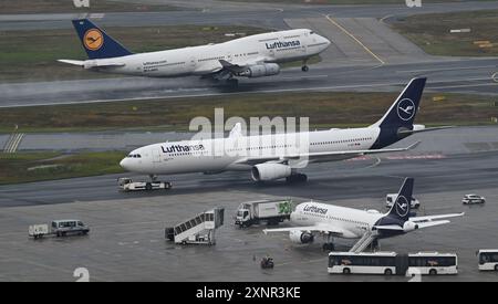 PRODUZIONE - 1 agosto 2024, Assia, Francoforte sul meno: Mentre un Boeing 747-400 (posteriore) Lufthansa decolla, un Airbus A330 viene trainato al Terminal 1 dopo l'atterraggio all'aeroporto di Francoforte. Foto: Arne Dedert/dpa Foto Stock