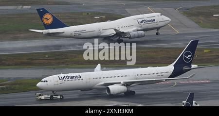 PRODUZIONE - 1 agosto 2024, Assia, Francoforte sul meno: Mentre un Boeing 747-400 (posteriore) Lufthansa decolla, un Airbus A330 viene trainato al Terminal 1 dopo l'atterraggio all'aeroporto di Francoforte. Foto: Arne Dedert/dpa Foto Stock