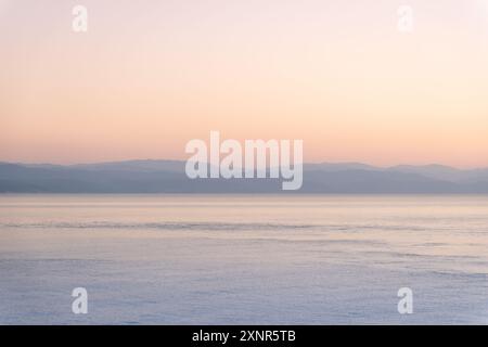 Tramonto sul Mar Nero a Batumi, Georgia. Il sole tramonta dietro le nuvole, proiettando un bagliore dorato sulle acque calme, creando un ambiente sereno e pittoresco Foto Stock