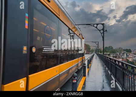 Treno della metropolitana giallo sul ponte Dom Luis i a Porto in un giorno coperto Foto Stock