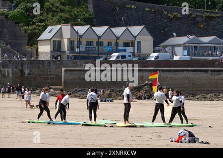 Un gruppo di principianti di surf che si preparano per una lezione di surf con un istruttore della scuola di surf SSS a Towan Beach a Newquay in Cor Foto Stock