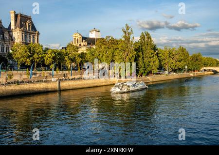 Vista della Senna dal Pont d'Arcole al tramonto, con escursione in barca che attraversa il fiume, il centro di Parigi, la Francia. Hôtel de Ville sullo sfondo Foto Stock