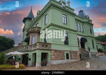 Edificio storico con facciata verde con torrette e caffetteria all'aperto a Porto al tramonto Foto Stock