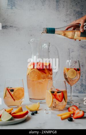 Versare a mano il vino nella caraffa di sangria bianca accanto ai bicchieri pieni. Foto Stock