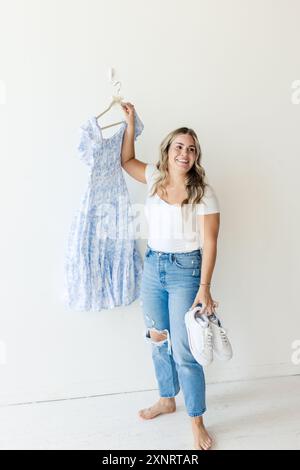 Donna in jeans con indosso un abito e scarpe da ginnastica, in piedi nudi Foto Stock