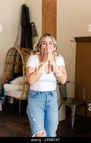Donna che copre la bocca a sorpresa, indossa camicia bianca e jeans Foto Stock
