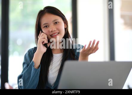 Una donna sta parlando al cellulare Foto Stock