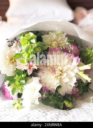 Un bouquet di fiori bianchi e viola con vegetazione, adagiato su una Foto Stock