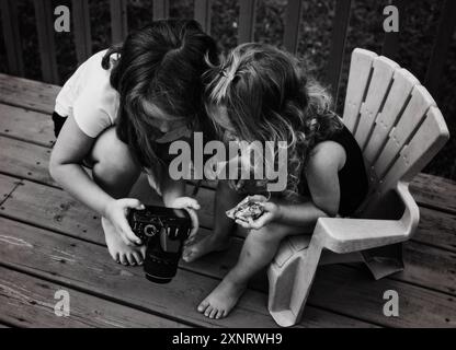 Giovani sorelle che scattano fotografie nel cortile posteriore Foto Stock