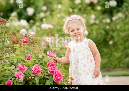 Bambina in giardino con le rose Foto Stock