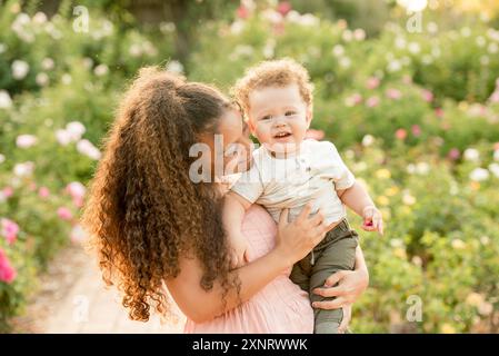 Sorella che tiene il fratello e sorride in giardino Foto Stock