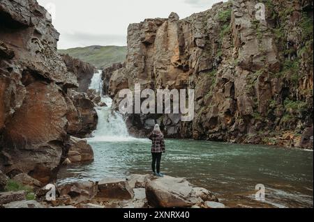 Donna in piedi su rocce, una cascata di Tofufoss, Islanda Foto Stock