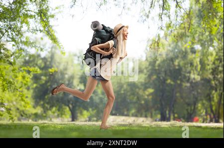 Immagine del profilo a tutta lunghezza di una donna backpacker che corre in un parco Foto Stock