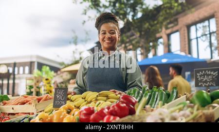 Ritratto di una donna multietnica di mezza età che gestisce uno stand di vendita di cibo di strada con prodotti agricoli biologici freschi. Felice ed elegante agricoltore africano guarda la fotocamera e sorride incredibilmente Foto Stock