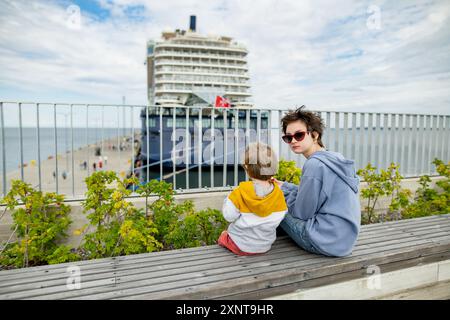 Il bambino carino e la sorella adolescente seduti su una panchina a guardare le navi da crociera attraccate nel porto di Tallinn. Foto Stock