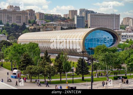Baku, Azerbaigian - 5 maggio 2024: I visitatori esplorano l'architettura unica e le mostre del Museo dei tappeti di Baku, circondato dal verde e dalla vita cittadina. Foto Stock