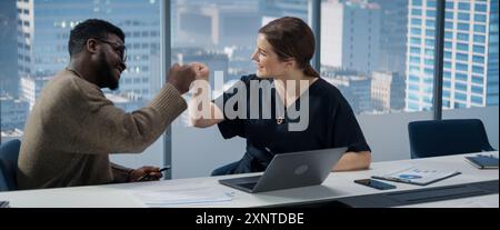 Uomini d'affari in Skyscraper Office: Riunione aziendale di due manager che utilizzano un notebook. CEO donna e direttore operativo afroamericano completano con successo un Task and Fist Bump. Foto Stock