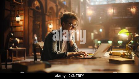 Tipizzazione mirata di un giovane su un laptop in una Majestic Library, illuminata da luce soffusa, calda, simboleggia la conoscenza, la creatività, e la ricerca dell'eccellenza letteraria. Foto Stock