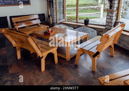 Aug2nd2024, Uttarakhand India. Moderno e semplice tavolo e sedia in legno massello in un caffè di montagna a Uttarakhand, India, che offre un accogliente luogo di ritrovo. Foto Stock