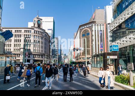 Edifici Mitsukoshi e Wako con persone che camminano lungo la Ginza al sole durante il fine settimana Hokoten, quando la strada è chiusa al traffico. Foto Stock