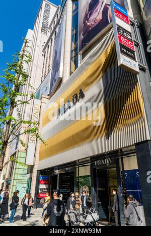 Ginza Core e il negozio Prada sulla Ginza con il suo design ardeggiato dorato e grigio sopra l'ingresso con il nome Prada in lettere argentate. Cielo blu. Foto Stock