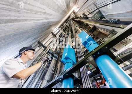 PRODUZIONE - 31 luglio 2024, Assia, Francoforte/M.: Markus Zink, tecnico di assistenza presso Schindler, ispeziona le funi metalliche nell'albero dell'elevatore alto 228,83 metri. Il produttore di ascensori Schindler testa vari componenti dei suoi ascensori nell'Europaturm, la torre televisiva di Francoforte. Foto: Lando Hass/dpa Credit: dpa Picture Alliance/Alamy Live News Foto Stock