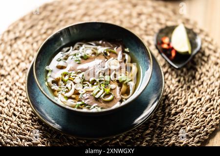 Zuppa vietnamita di spaghetti di riso fresco con manzo, cipolle, lime, erbe aromatiche e peperoncino. Foto Stock