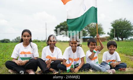 Gruppo di studenti o bambini che indossano una maglietta tricolore indiana, volto dipinto con triclolor e saluto. Festeggiamo l'indipendenza o il giorno della Repubblica. Har Ghar Foto Stock