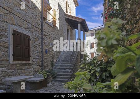 Un vicolo con una serie di gradini in pietra che conducono ad una porta in legno posta all'interno di un vecchio edificio in pietra Foto Stock