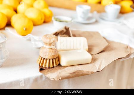 Primo piano di due pezzi di sapone fatto a mano e di spazzolina di bambù per lavare i piatti su carta artigianale. Sapone profumato e spazzola realizzati con materiali naturali su Foto Stock