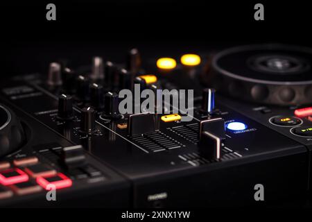 Primo piano di un mixer DJ con pulsanti e manopole luminosi in un ambiente buio, mixer audio dj Foto Stock