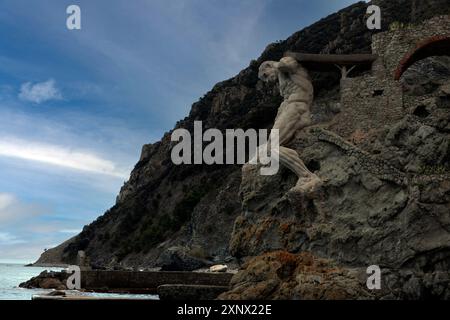 Il Gigante, una scultura in pietra raffigurante Nettuno, dio romano del mare, alla fine della spiaggia di Fegina, Monterosso al Mare, cinque Terre, Italia Foto Stock