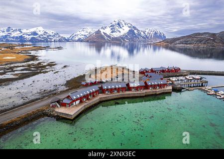 Vista aerea del tradizionale rorbu rosso circondato da maestose montagne ricoperte di neve, Vestvagoy, isole Lofoten, Norvegia, Scandinavia, Europa Foto Stock