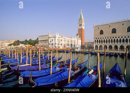 Gondole ormeggiate a Riva degli Schiavoni con il Palazzo dei Dogi e il Campanile di San Marco, Venezia, UNESCO, regione Veneto, Italia Foto Stock